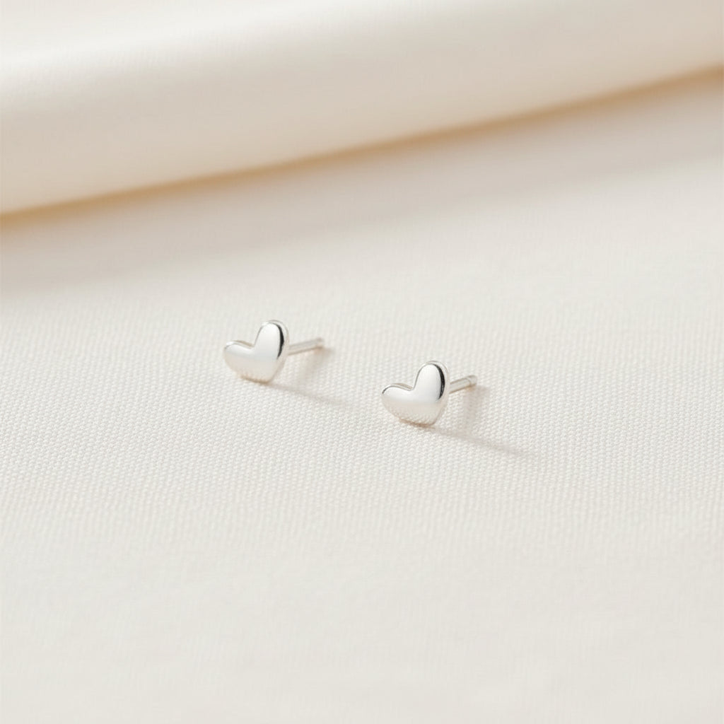 Heart-shaped silver earrings on a light gray background