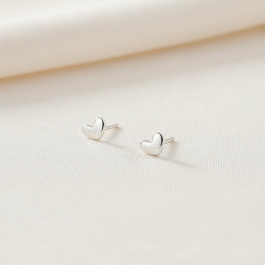 Heart-shaped silver earrings on a light gray background