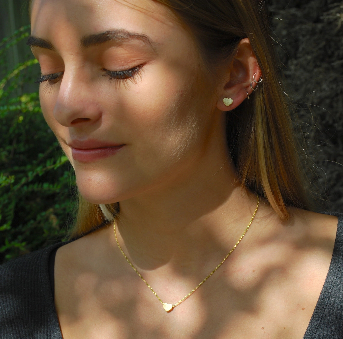 Woman wearing a gold necklace with heart pendants outdoors