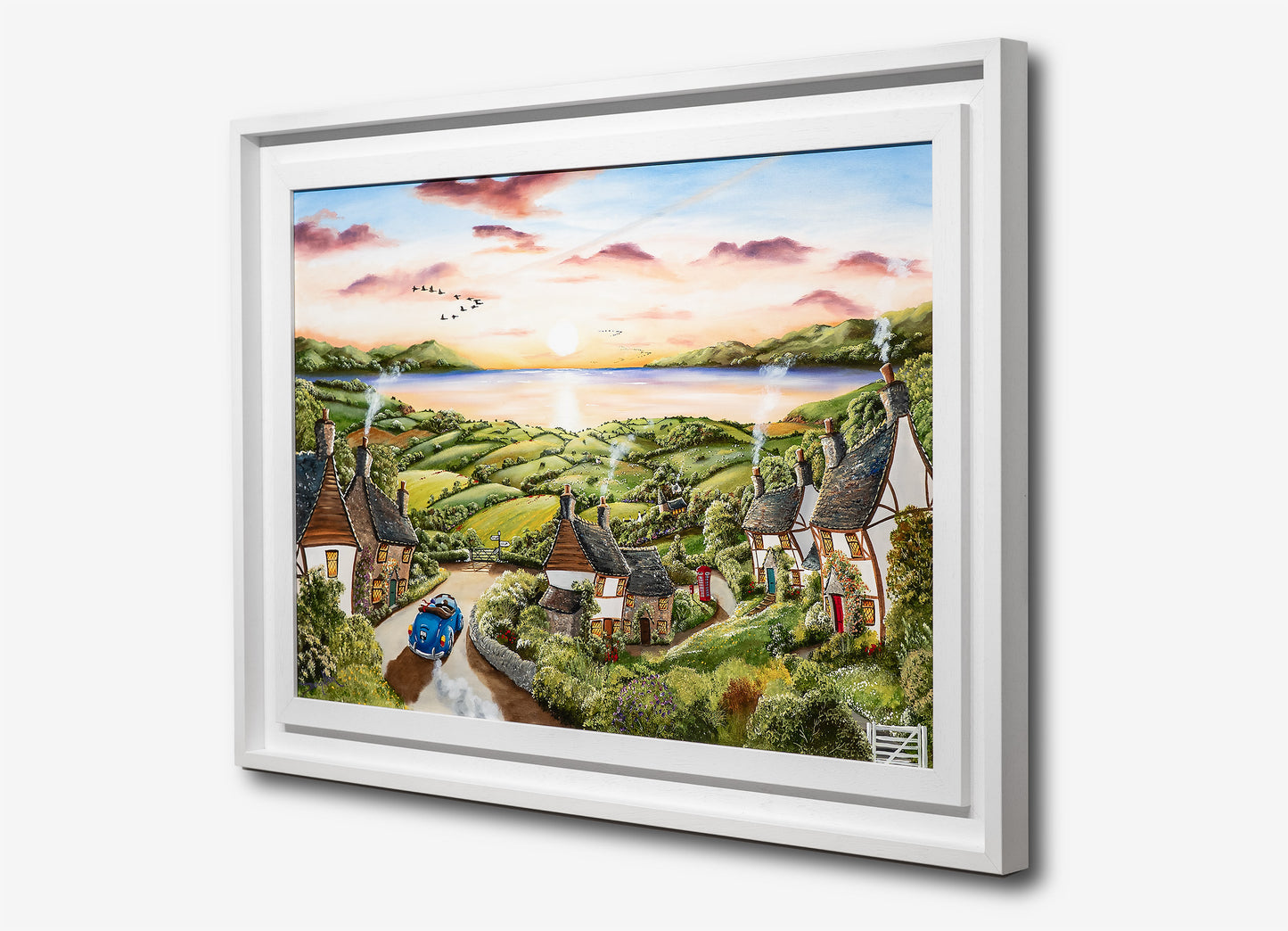 Framed artwork of a scenic landscape with houses and a lake. Caroline Deighton painting