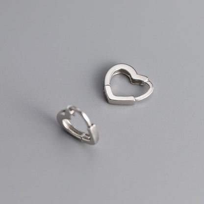 Two silver heart-shaped hoop earrings on a gray background