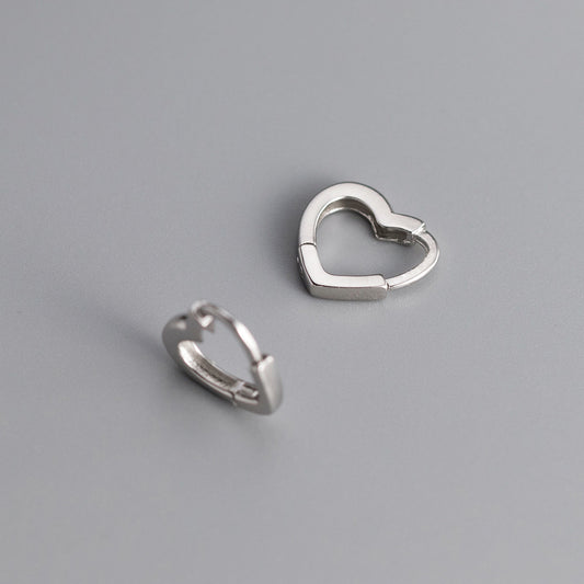 Two silver heart-shaped hoop earrings on a gray background