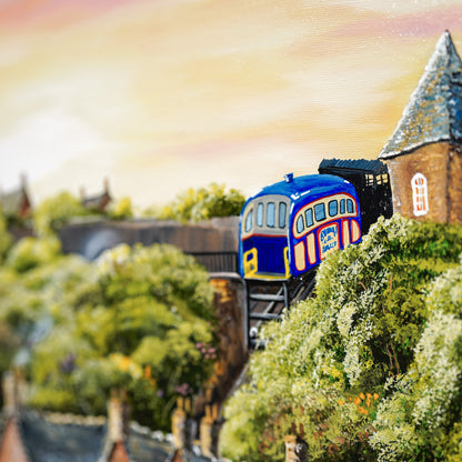 Painting of a blue and red train passing through a town with houses and trees.