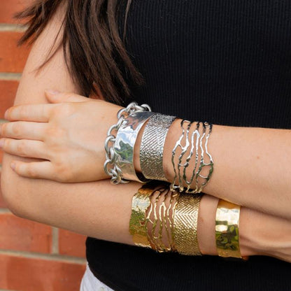 Person wearing multiple bracelets on arms with a brick wall background