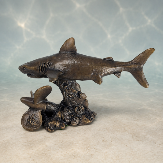 Bronze-finished shark aquarium ornament mounted on a rocky coral base, displayed against a water-ripple background.