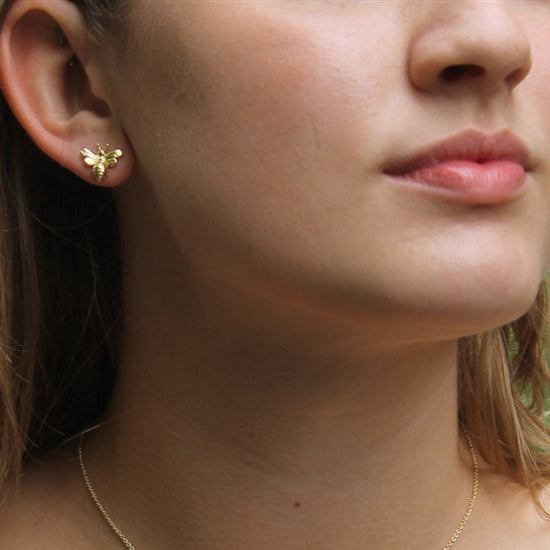 Close-up of a person wearing a gold necklace with a butterfly pendant.