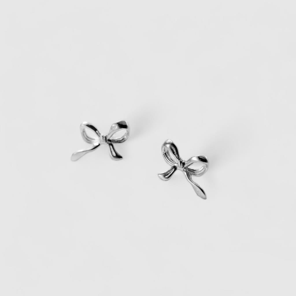 Silver bow-shaped earrings on a light gray background