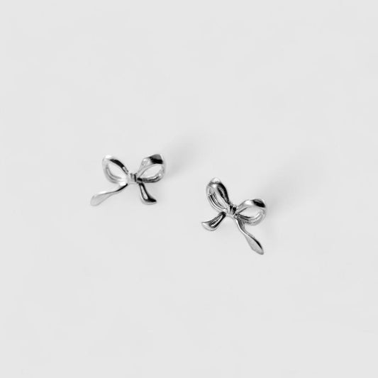 Silver bow-shaped earrings on a light gray background