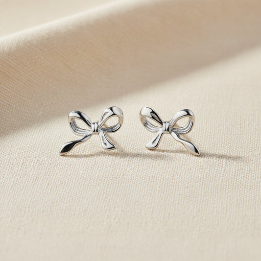 Silver bow-shaped earrings on a white background