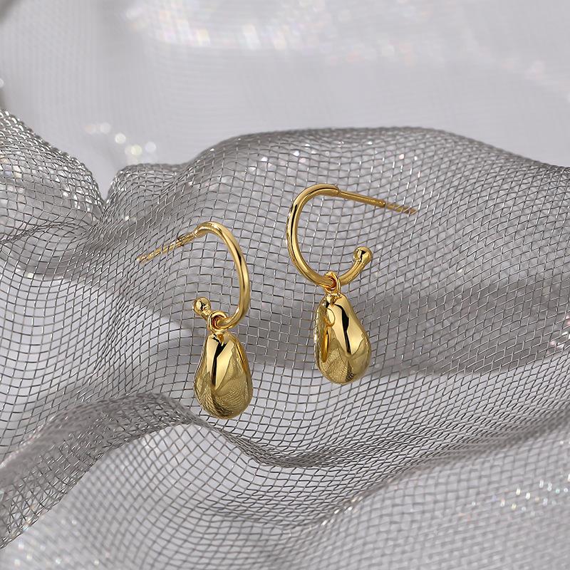 Gold earrings on a silver mesh background