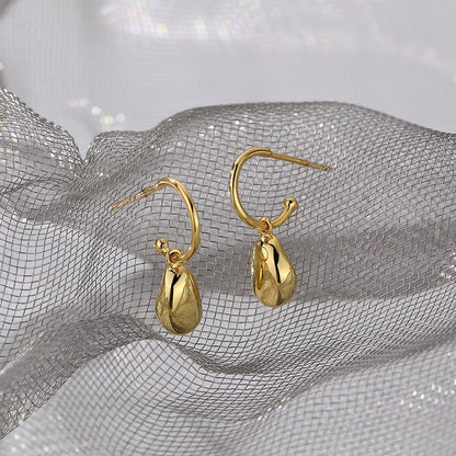 Gold earrings on a silver mesh background