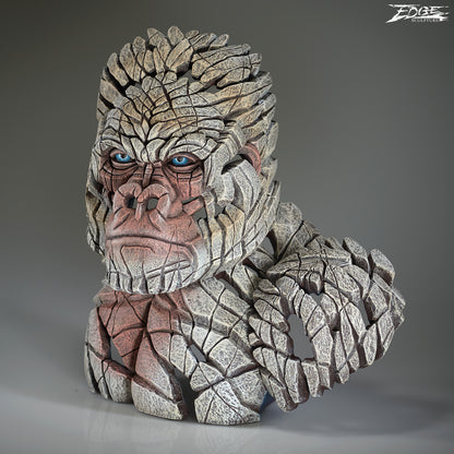 Stone-like sculpture of a mountain gorilla with blue eyes on a gray background