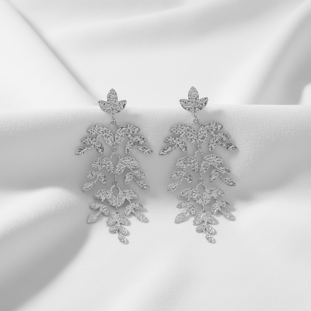 A pair of silver-toned dangle earrings with a cascading, leaf-like design set with clear rhinestones, shown against a plain white background.