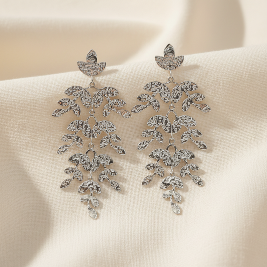 A pair of silver-toned dangle earrings with a cascading, leaf-like design set with clear rhinestones, shown against a plain white background.