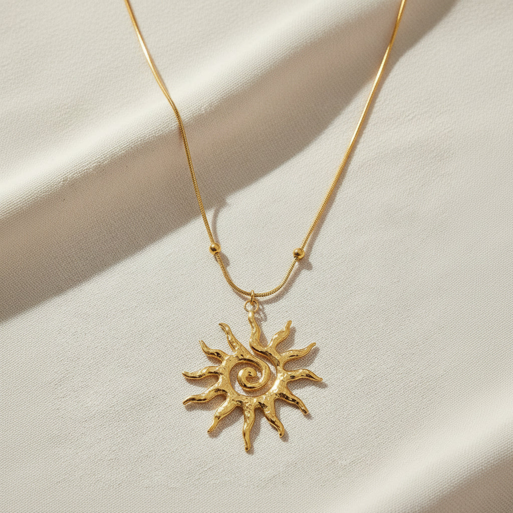 Gold sun-shaped pendant necklace on a white background
