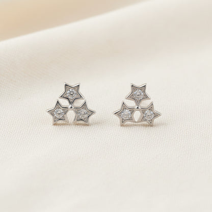 Pair of silver star-shaped earrings on a light gray background