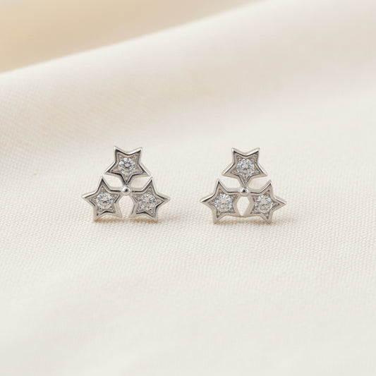 Pair of silver star-shaped earrings on a light gray background