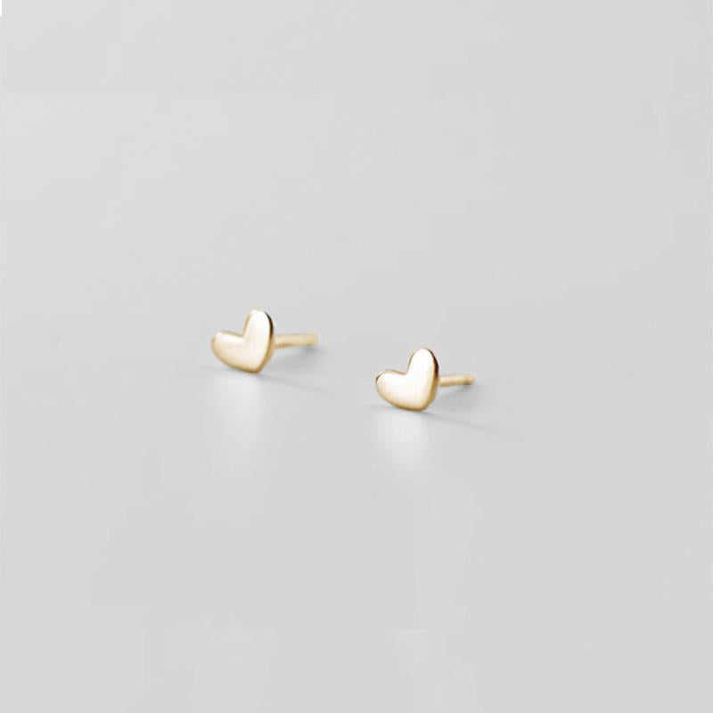 Gold heart-shaped earrings on a light gray background