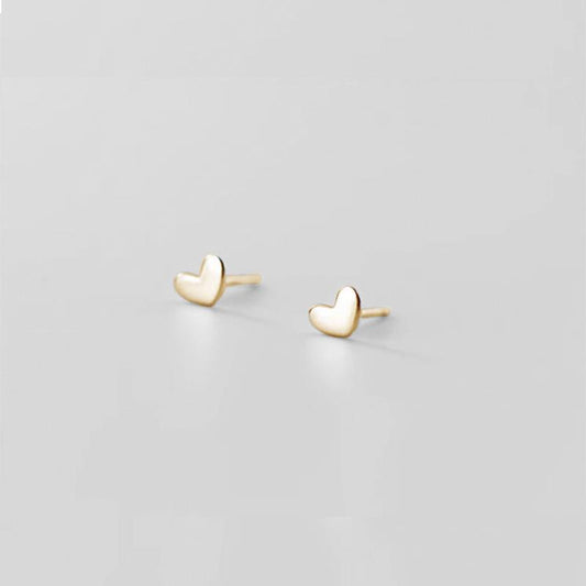 Gold heart-shaped earrings on a light gray background