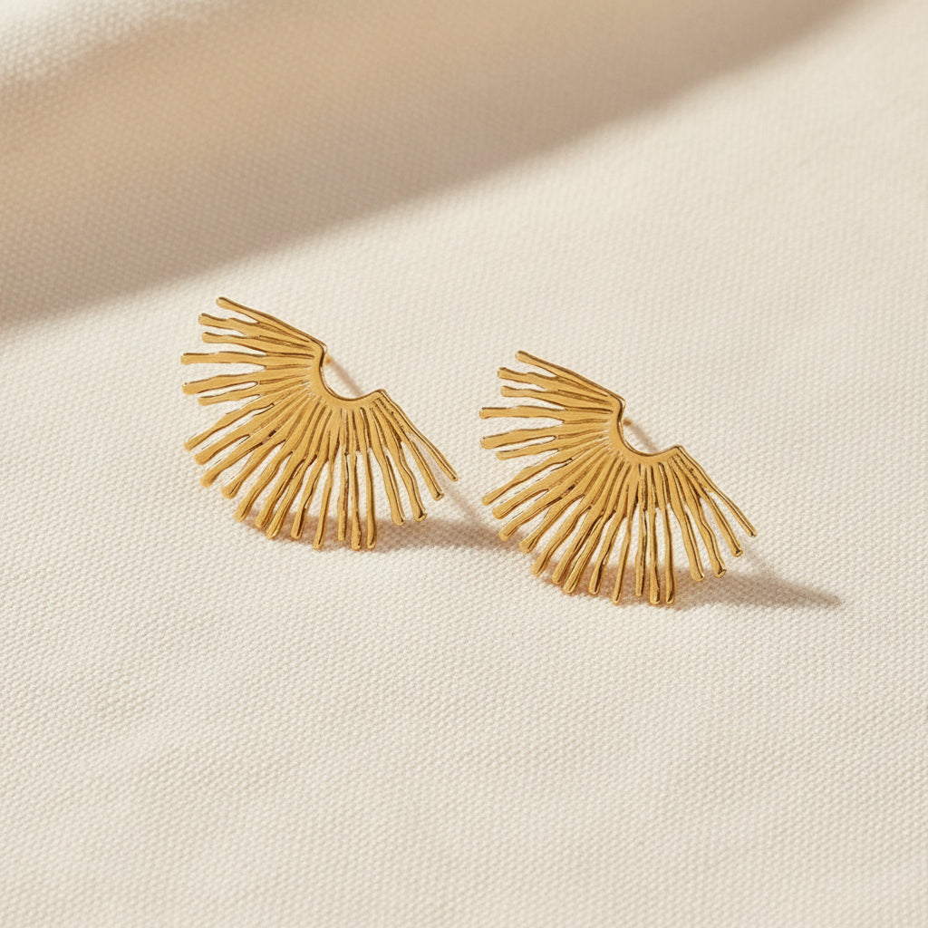 Gold earrings with a fan-like design on a white background