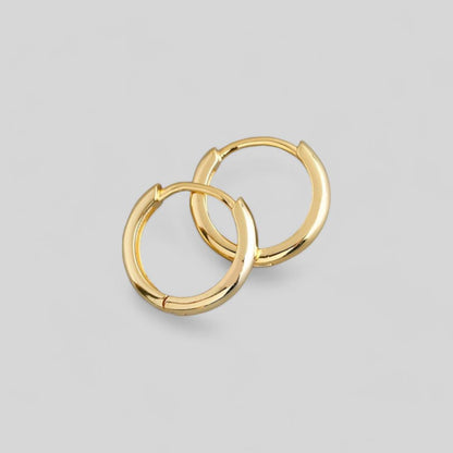 Pair of gold hoop earrings on a light gray background