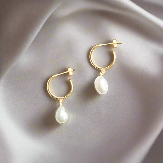 Gold hoop earrings with pearl drops on a white background