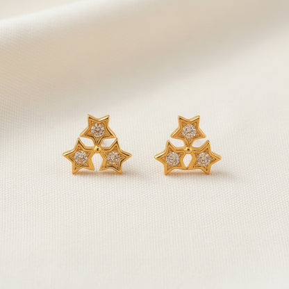 Pair of gold star-shaped earrings on a light gray background
