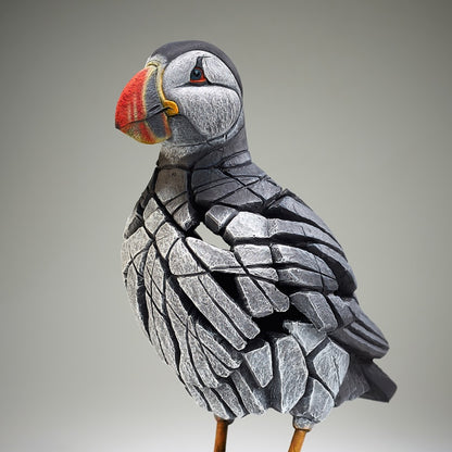 Stylized puffin sculpture with a gray and orange beak on a neutral background